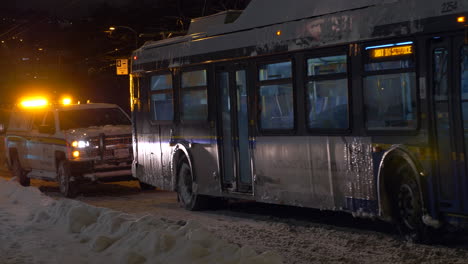 Condado-De-Hastings-En-Ontario,-Canadá---Un-Automóvil-Y-Un-Autobús-Moviéndose-Lentamente-En-Un-Camino-Nevado-En-Una-Noche-De-Invierno---Tiro-Medio