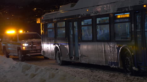 Hastings-County-in-Ontario,-Canada---A-Car-And-A-Bus-Moving-Slowly-In-A-Snowy-Road-On-A-Winter-Night---Medium-Shot