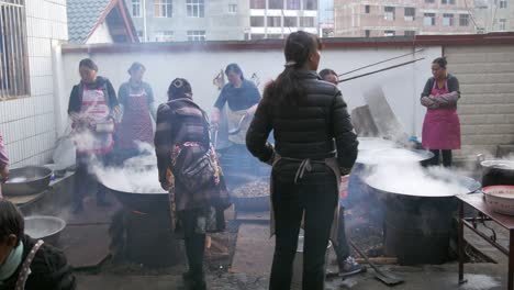 Eine-Gruppe-Von-Frauen,-Die-Riesige-Dampfende-Reisschalen-Zur-Vorbereitung-Auf-Die-Chinesische-Hochzeit-In-Weixi,-Yunnan,-Zubereiten