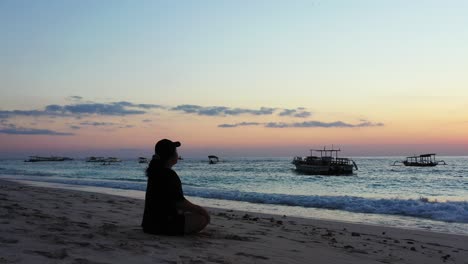 Sporty-woman-with-a-hat-meditation-in-the-early-morning-on-the-peaceful-sandy-beach