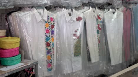 Camera-turns-to-right-showing-assortment-of-guayabera-men’s-shirts-in-Merida,-Mexico