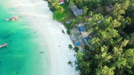 Turquoise-calm-lagoon,-sand-beach-and-colorful-bungalows-on-the-beachfront