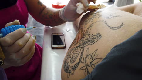 Cerca-De-Un-Tatuador-Pintando-Una-Serpiente-En-La-Pierna-De-Un-Cliente-Blanco