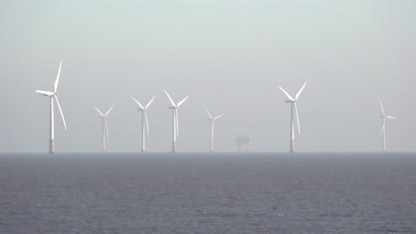 Ein-Schiff-Fährt-Hinter-Den-Sich-Drehenden-Turbinenblättern-Des-Riesigen-Windparks-Lincs-Vorbei,-Der-Acht-Kilometer-Vor-Der-Küste-Der-Nordsee-Vor-Der-Ostküste-Englands-Liegt