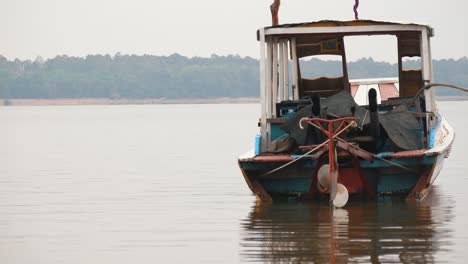 Medium-Shot-of-a-Small-Abandoned-Asian-Fishing-Boat-Floating-Near-the-Shore
