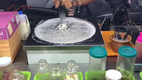 A-skilled-chef-making-a-modern-ice-cream-roll-in-a-vendor-cart-in-Bangkok,-Thailand
