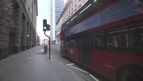 A-dead-and-empty-street-at-Bishopsgate-in-central-London-with-a-single-bus-driving-by-during-coronavirus-lockdown-and-self-isolation