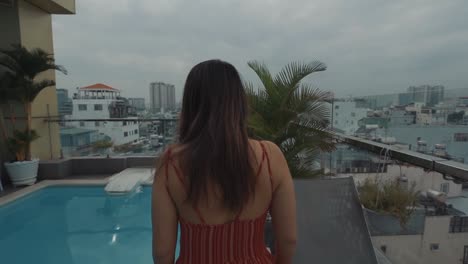 Mujer-Joven-Caminando-Junto-A-Una-Piscina-En-La-Azotea