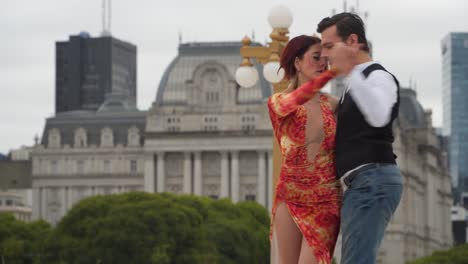 A-couple-of-tango-dancers-dancing-with-Kirchner-cultural-centre-on-background