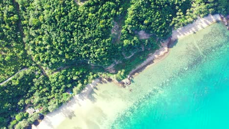 Paradiesischer-Unberührter-Strand-Mit-Weißem-Sand-Unter-üppiger-Vegetation,-Umspült-Von-Einer-Ruhigen-Türkisfarbenen-Lagune-Mit-Wunderschönen-Korallen-In-Myanmar