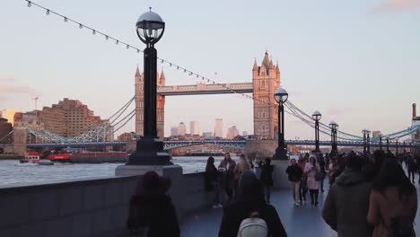 Handheld-walking-together-with-crowds-of-Londoner-people-and-tourists-on-the-riverside-near-Tower-Bridge