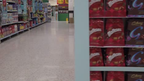 Slow-motion-interior-empty-UK-supermarket-dolly-left-passing-sweets-aisle