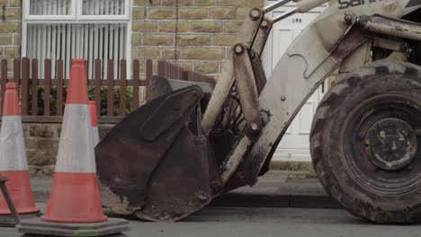 Excavadora-De-Plantas-Pesadas-Y-Conos-De-Carretera-Estacionados-En-La-Calle