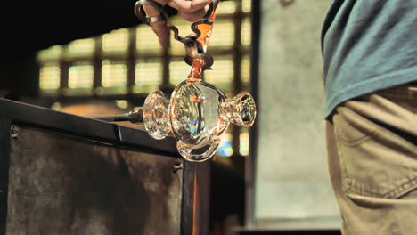 Glass-artist-cuts-off-section-of-molten-glass-during-the-glass-blowing-process