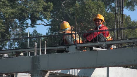 Toma-Amplia-De-Dos-Tipos-De-Construcción-En-El-Techo-De-Un-Edificio-En-Un-Sitio-De-Construcción-Descansando-Bajo-El-Sol-Caliente