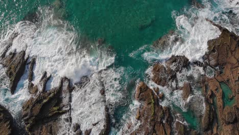 Panning-view-from-above-shows-the-rocky-shores-of-Porto-das-Salemas-being-hit-with-waves-from-the-turquoise-waters-of-the-ocean