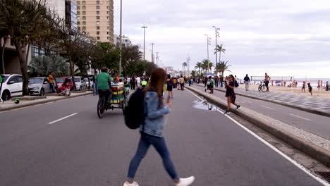 People-walking-by-the-beach-during-a-protest-in-Rio-de-Janeiro,-Brazil