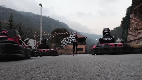 Wide-Low-Angle-Shot-Of-Attractive-Lady-Waving-Chequered-Flag-To-Start-Go-Kart-Race