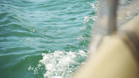 Closeup-of-water-splashing-on-side-of-boat,-moving-through-water