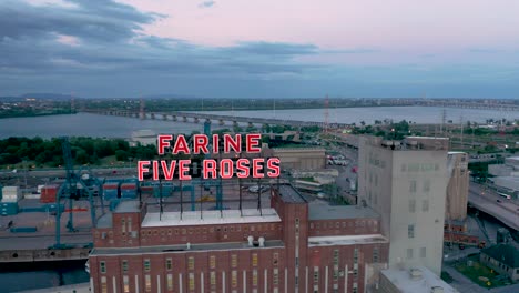 Drone-Moviéndose-Frente-Al-Icónico-Edificio-Farine-Cinco-Rosas-Que-Revela-El-Río-St-lawrence