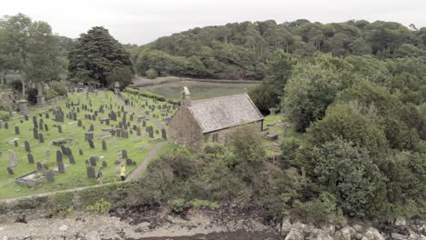 Visitors-walking-through-graveyard-at-Tysillio-church-island-on-Menai-Straits-Anglesey-Wales-Aerial-view