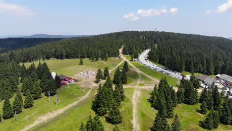 Rogla-Slovenia-hiking-trails-during-spring-season-passing-through-ski-lift-area-near-the-parking-lot,-Aerial-flyover-shot