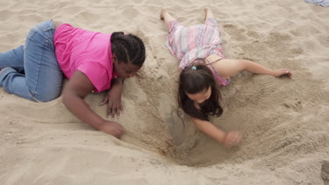 Two-Young-Girls-at-the-Beach-Dig-as-Friends,-Slow-Motion