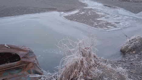 Pan-left-to-reveal-an-old-rusty-abandoned-car-embedded-in-the-ground-on-the-river-bank-of-the-Knik-river-near-Eklutna-Tailrace-area-near-Palmer-Alaska