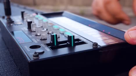 Side-view-of-girl-playing-analogue-electronic-musical-loop-synth-instrument-and-changing-the-setting-on-the-instrument-mid-open-air-concert