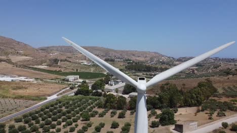 Aerial:-wind-turbine-turning-on-mediterranean-hillside,-closeup-reveal