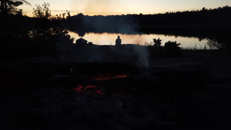 Feuer-Im-Vordergrund-Und-Einsame-Gestalt-In-Der-Abenddämmerung-Im-Hintergrund