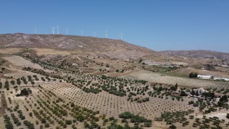 Aerial-view:-wind-turbines-on-European-hilltop,-turning-in-wind-in-distance