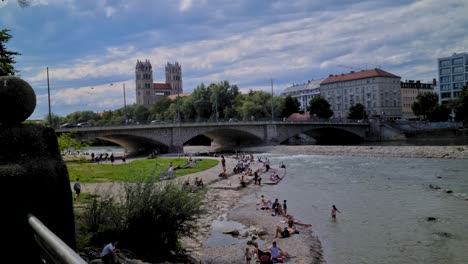 Traffic-on-Reichenbach-Bridge-On-Isar-River-and-People-on-Riverbank,-Munich-City-Germany