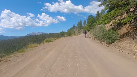 Punto-De-Vista-Pasando-A-Un-Ciclista-De-Montaña-Mientras-Conduce-Por-Un-Paso-De-Montaña-De-Grava-En-Las-Montañas-Rocosas-De-Colorado---Emocionante-Expedición-Todoterreno