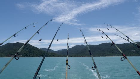 Fishing-rods-hanging-from-back-of-boat-facing-mountains-in-distance