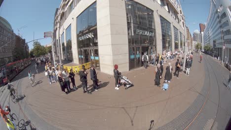 Vista-De-Ojo-De-Pez-De-Las-Personas-En-La-Cola-Fuera-De-Una-Tienda-Minorista-Primark-En-La-Haya,-Países-Bajos---Pandemia-De-Coronavirus---Nueva-Normalidad