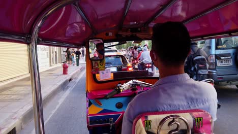 Un-Tuk-Tuk-Navegando-Por-El-Lado-Izquierdo-De-La-Carretera-En-Bangkok-Visto-Desde-El-Asiento-Del-Pasajero-Durante-La-Hora-Pico-Mientras-La-Gente-También-Se-Ve-En-La-Acera