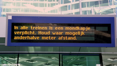 Electronic-sign-informing-passengers-that-a-mouth-mask-is-mandatory-in-all-trains,-and-to-keep-one-and-a-half-meter-distance-if-possible