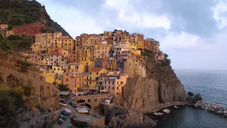 Wide-angle-shot-revealing-the-village-of-Manarola-in-Cinque-Terre-at-sunset,-Liguria,-Italy,-a-UNESCO-World-Heritage-Site,-famous-for-its-coastline,-five-villages-and-surrounding-hillsides