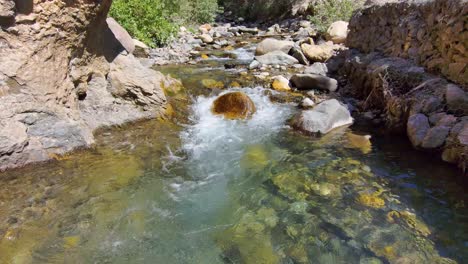Flying-close-above-the-surface-of-a-fresh-water-mountain-stream-in-a-rocky-canyon---pull-back