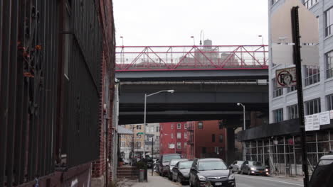 Subway-Above-Ground-Goes-By-With-Bikers-in-Williamsburg-Brooklyn,-Long-Steady-Shot,-Establishing