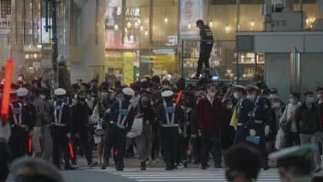 Policías-Alineados-En-La-Carretera-Controlando-A-La-Multitud-En-El-Cruce-De-Shibuya-Durante-La-Noche-De-Halloween-En-Tokio,-Japón---Cámara-Lenta