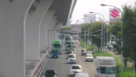 Trucks-And-Cars-Slowly-Moving-On-The-Road-With-Light-Traffic-In-Saitama,-Japan---high-angle-shot