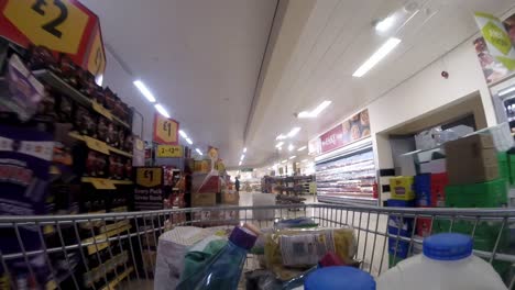 Inside-supermarket-shopping-cart-pushing-trolley-down-deli-aisle-as-customers-shop-during-corona-virus-pandemic