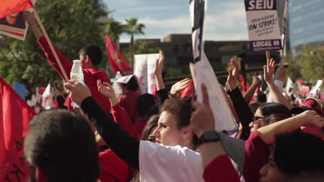 Diverse-Crowd-Raises-Signs-and-Cheers,-Large-Crowd,-Red-and-White,-Slow-Motion