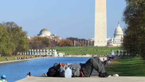 A-man-who-appears-to-be-unhoused-naps-during-a-fall-day-the-National-Mall-in-Washington,-D