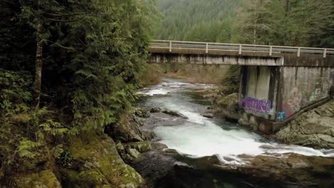 Bridge-crosses-Washougal-River-with-graffiti-on-one-side,-aerial-slow-motion