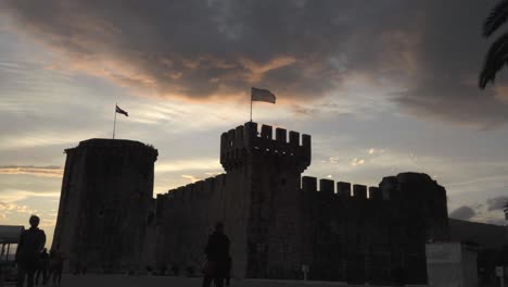 Torre-Kamerlengo,-En-La-Ciudad-De-Trogir-En-Croacia,-Al-Atardecer-Con-Nubes-Rojas-Y-Violetas-Soplando-En-El-Fondo