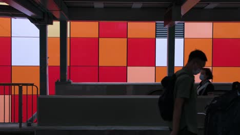 Commuters-are-seen-walking-on-a-pedestrian-bridge-as-they-pass-by-a-colorful-wall-in-Hong-Kong