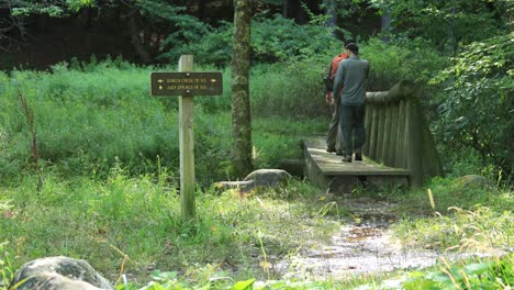 Two-men-cross-a-footbridge-at-Judy-Springs,-within-the-Spruce-Knob-Seneca-Rocks-National-Recreation-Area-in-West-Virginia